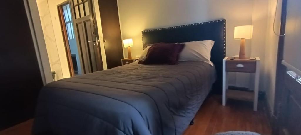 a bedroom with a large bed with a blue headboard at Alquiler de habitación, con baño privado. in Buenos Aires