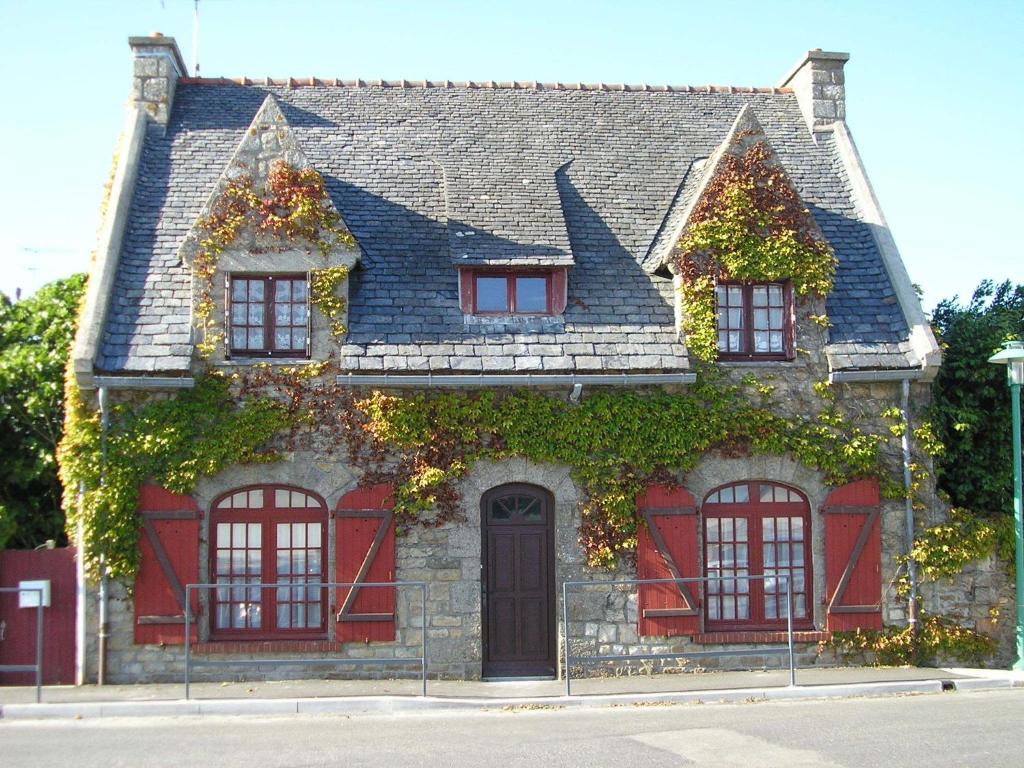 una casa con porte rosse e edera sopra di Chambre d'hôtes La Maison du Neuilly a Le Conquet