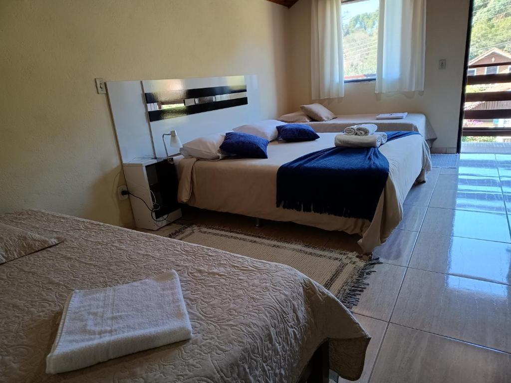 a bedroom with two beds and a window at Estalagem Brumone in Monte Verde