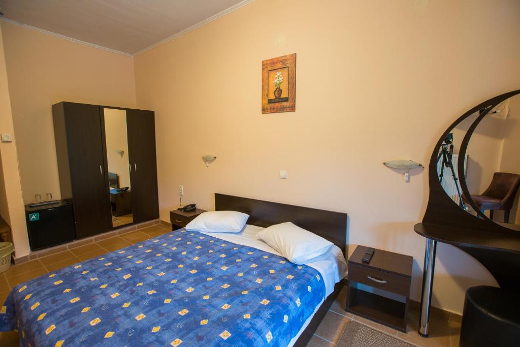 a bedroom with a bed with a blue blanket at Hotel Tzoumerka in Pramanta