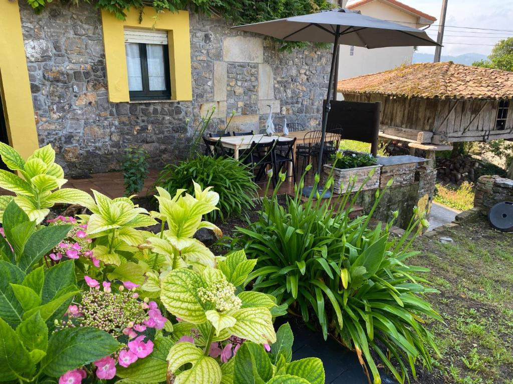 a garden with a table and an umbrella and flowers at LOS CARBAYINOS in Villaviciosa