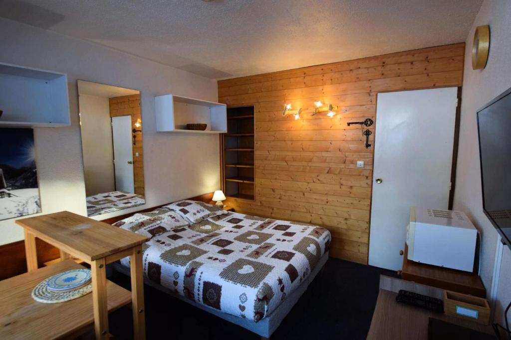 une chambre avec un lit et un mur en bois dans l'établissement Résidence Le France - Studio 2 pers - LE FRANCE - PLAGNE CENTRE MAE-5904, à Aime La Plagne