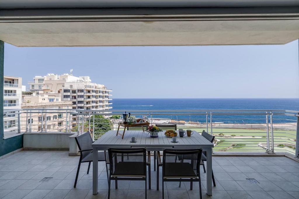 a table on a balcony with a view of the ocean at 602 Sliema 3bed Seafront With Pool By Homely in Sliema
