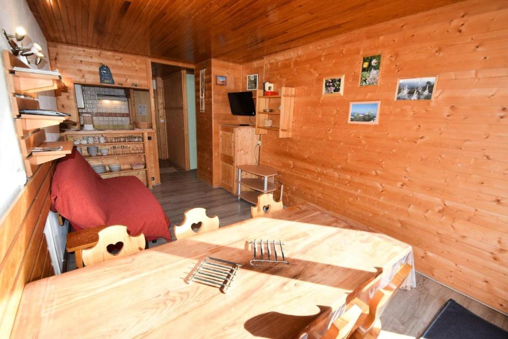 Cette chambre est dotée de murs en bois et d'une table. dans l'établissement Résidence Le Jannu - 2 Pièces 5 pers - LE JANNU - PLAGNE CENTRE MAE-8974, à Aime La Plagne