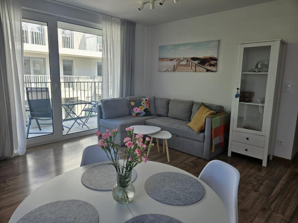 a living room with a couch and a table with flowers at Apartament Cuma - zacumuj w Pucku in Puck