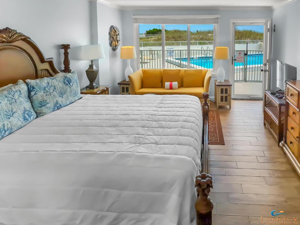 a bedroom with a large bed and a yellow couch at Cozy Studio Beachfront Condo - Romantic Getaway! in Fort Walton Beach