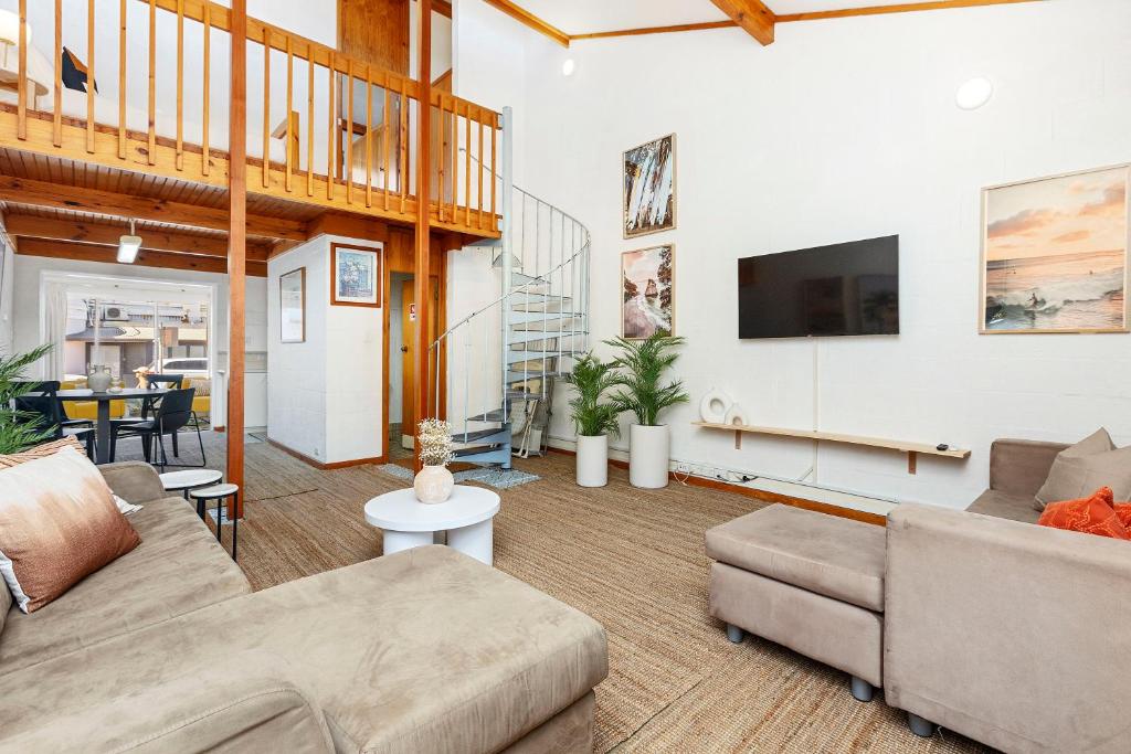 a living room with a couch and a tv at 11 Cottesloe - steps from beach - sleeps 3 in Perth