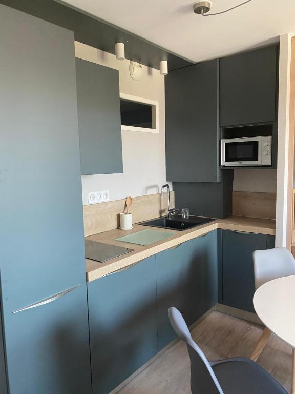 une cuisine avec des armoires bleues et une table et des chaises dans l'établissement T2 cozy à 1km de Saint Charles, à Marseille