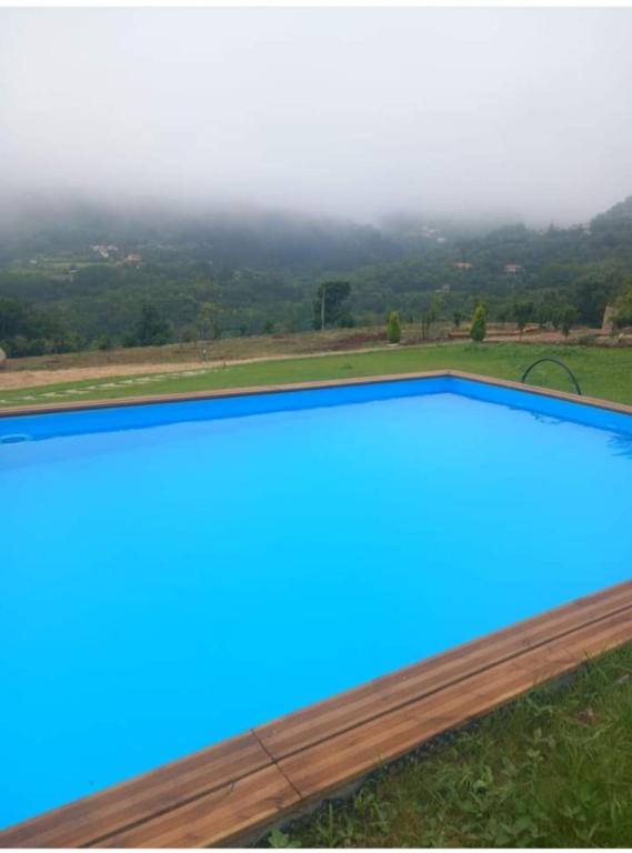 a blue swimming pool with a view of the mountains at Casa de Silvares in Celorico de Basto