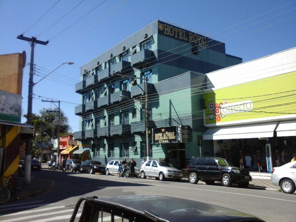 een gebouw aan een drukke straat met geparkeerde auto's bij Hotel Royal Class in Guaratinguetá