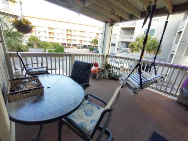 a porch with a swing and a table and chairs at Dragonfly Daze villa in Carolina Beach