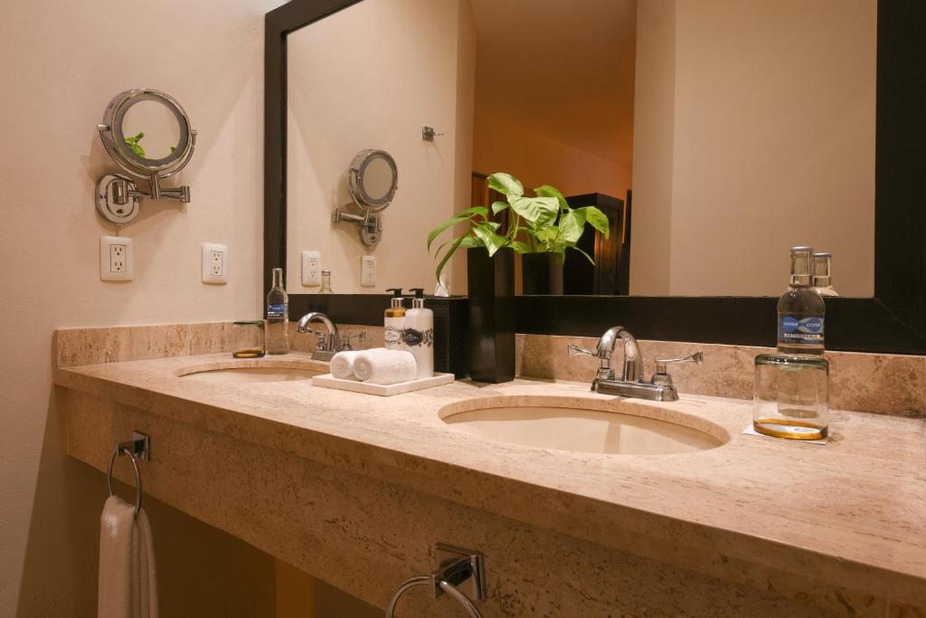 a bathroom with two sinks and a large mirror at Hidden Beach Resort Au Naturel Adults Only Catamarán, Cenote & More Inclusive in Akumal