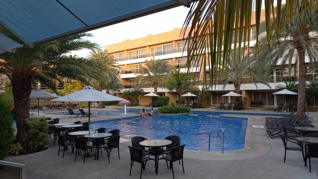 una piscina con mesas y sillas y un hotel en Hotel Margarita Real Penthouse 6403, en Porlamar