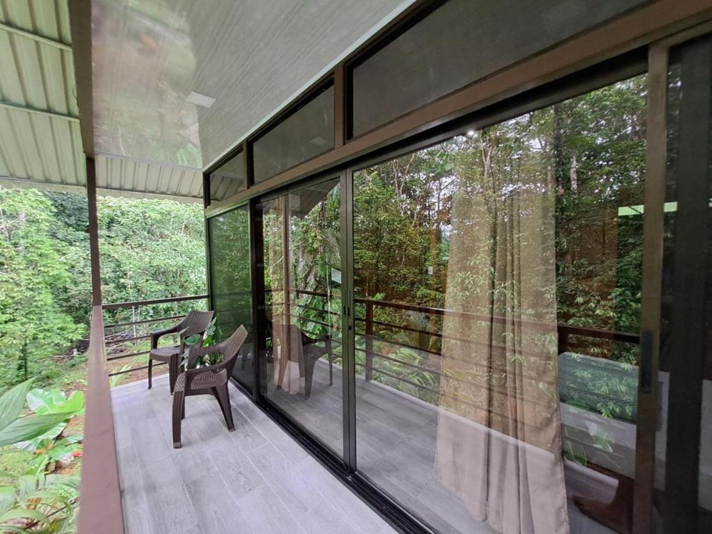 une maison de verre dans les bois avec un banc sur le balcon dans l'établissement La Amapola Lodge, Bungalow en Península de Osa., à Barrigones