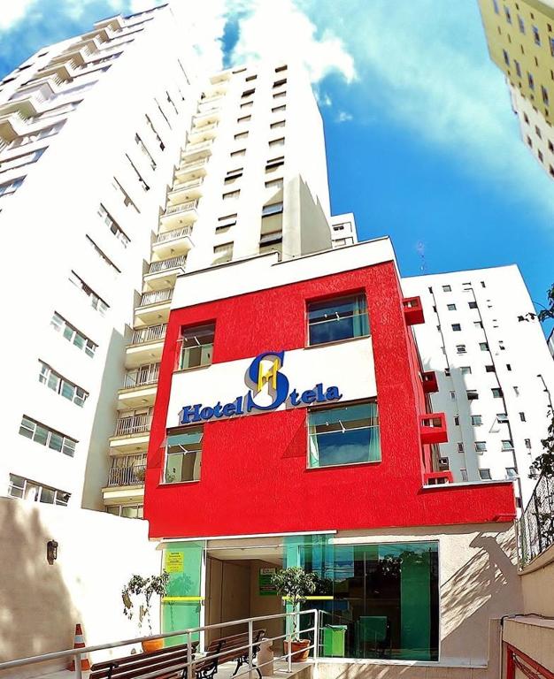a red and white building with a blue sign on it at Hotel Stela - A 2 min do Metrô Paraíso e Poucos Passos da Av Paulista in São Paulo