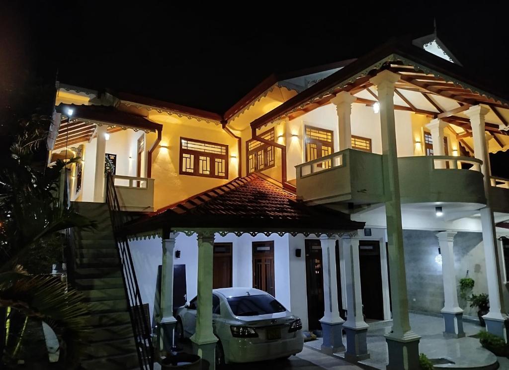une voiture garée devant une maison la nuit dans l'établissement White Palace, à Negombo