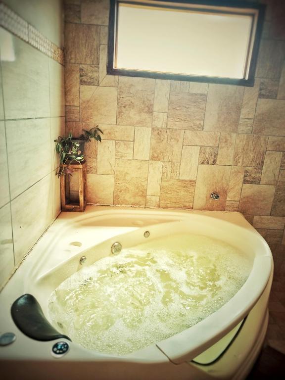 a bath tub in a bathroom with a window at Chalé Angico - Refúgio Namata in Pirenópolis