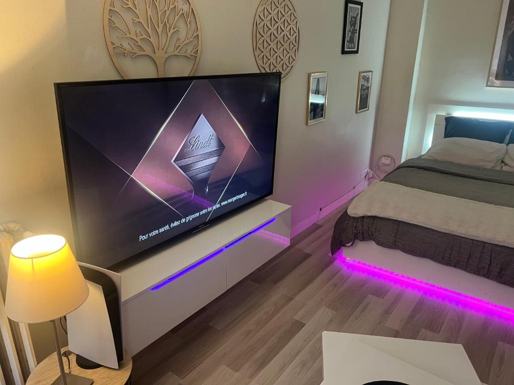 une chambre avec une grande télévision avec des lumières violettes dans l'établissement Appartement gare Nice ville, à Nice