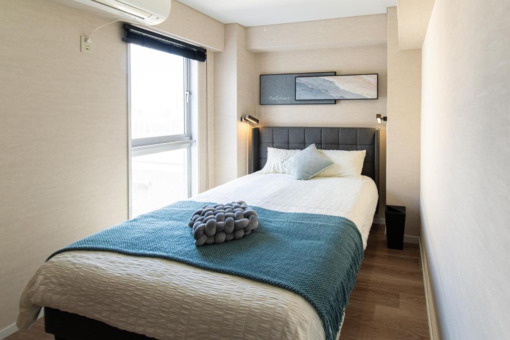 a bedroom with a bed with a blue blanket and a window at Z7全新装修套房3室2厅 新宿2站4分钟,Max 8p-spacious,3rooms Near Shinjuku in Tokyo