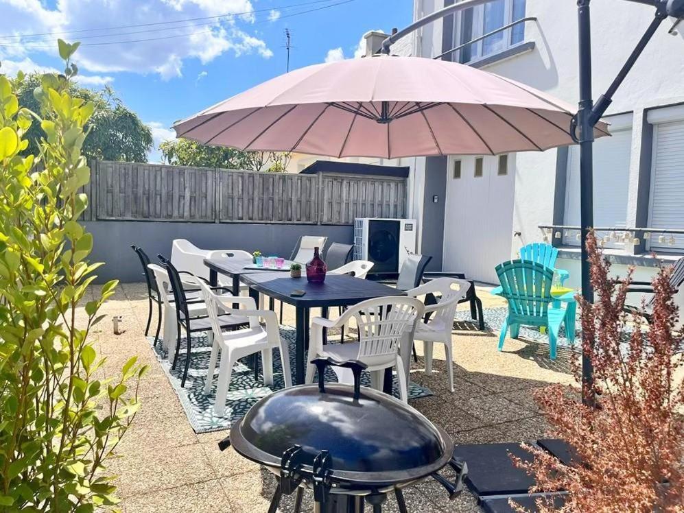 un patio avec une table, des chaises et un parasol dans l'établissement La maison d'anne-claire, à Ploemeur