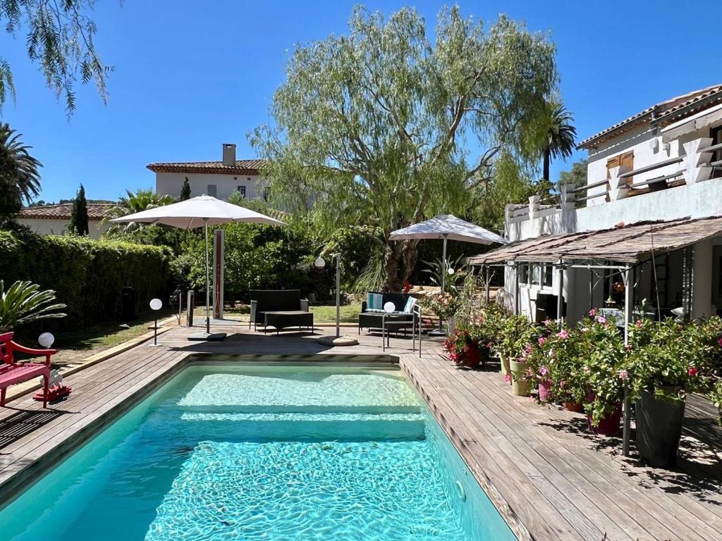 - une piscine sur une terrasse en bois à côté d'une maison dans l'établissement Bas de villa avec piscine privée, grande terrasse, proche village et plage, BBQ, terrain de pétanque - FR-1-726-52, à La Croix-Valmer