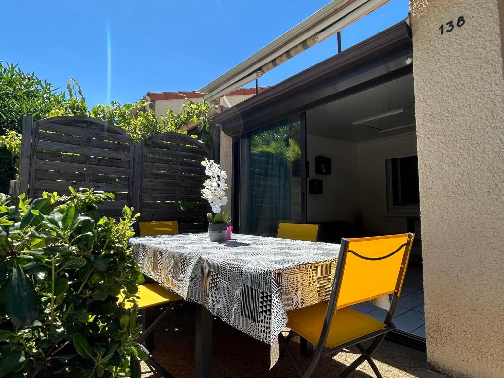 - une table à manger avec des chaises jaunes sur la terrasse dans l'établissement Pavillon Refait à Neuf à Argelès-sur-Mer, Climatisé avec Wi-Fi, Terrasse et Piscine, Proche Plage - FR-1-732-82, à Argelès-sur-Mer