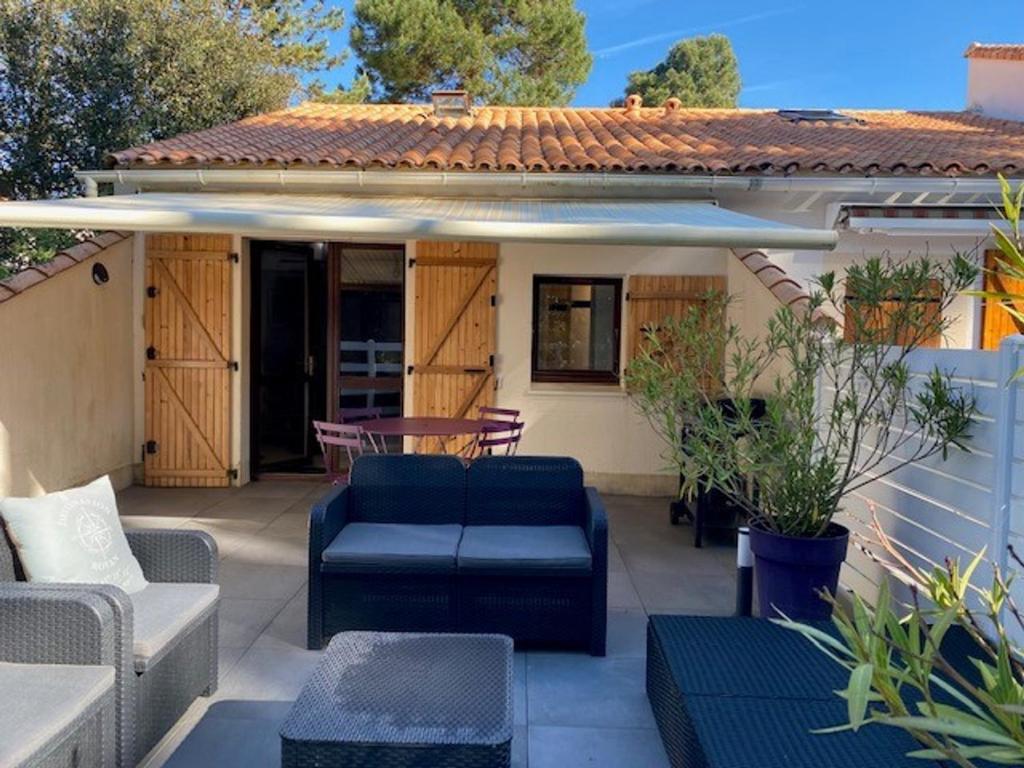 une terrasse avec des canapés et des tables ainsi qu'une maison dans l'établissement Maisonnette de Vacances à 200m de la Plage avec Terrasse à Saint-Georges-de-Didonne - FR-1-550-84, à Saint-Georges-de-Didonne