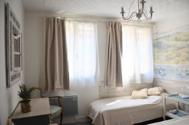 a bedroom with a bed and a chandelier and windows at Petite chambre avec 2 lits dans maison d'artiste centre ville in Bernay