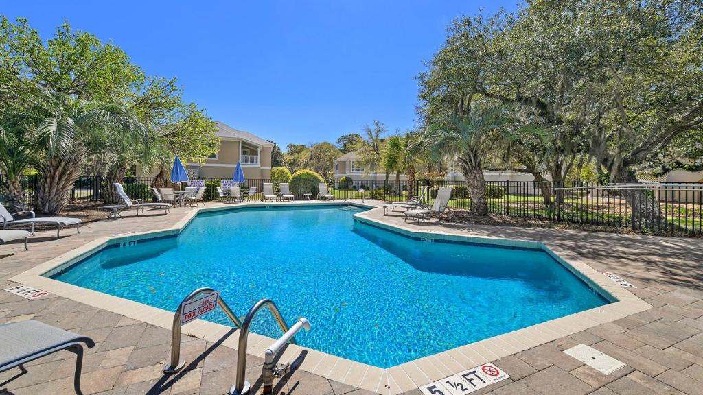a swimming pool in a yard with chairs and trees at Poolside at DeBordieu Colony in Georgetown