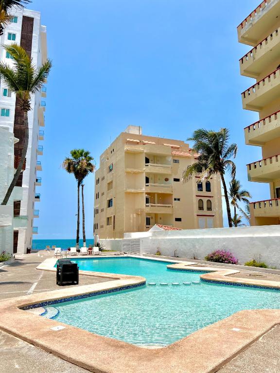 a swimming pool with palm trees and buildings at Marina del Sol 402 Vista al Mar in Mazatlán