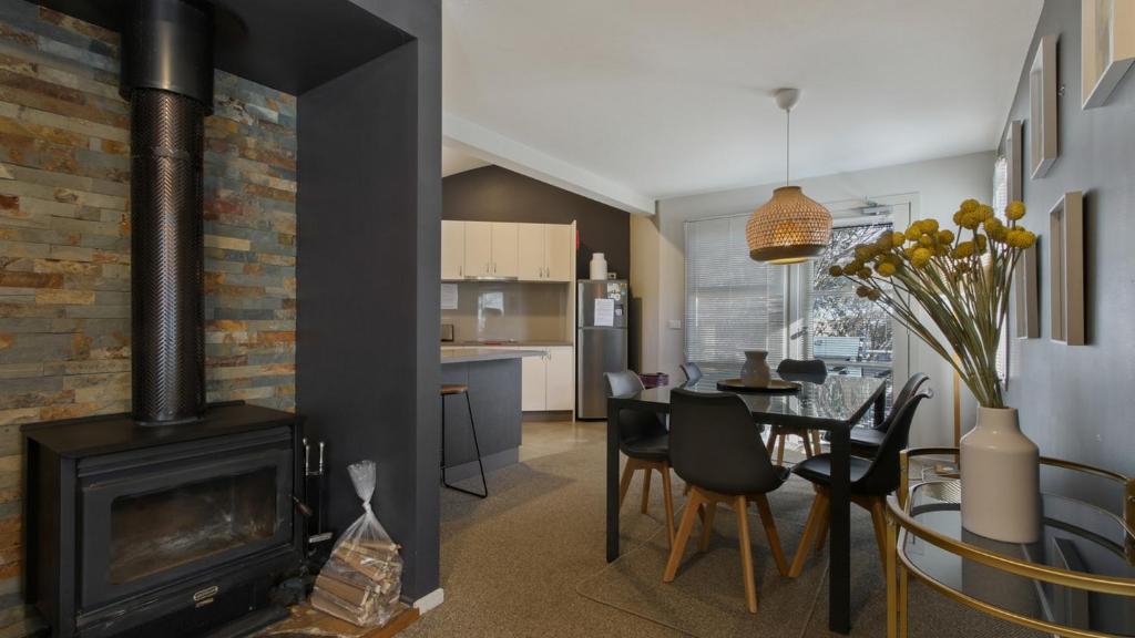 a living room with a fireplace and a dining room at Numbawan in Dinner Plain