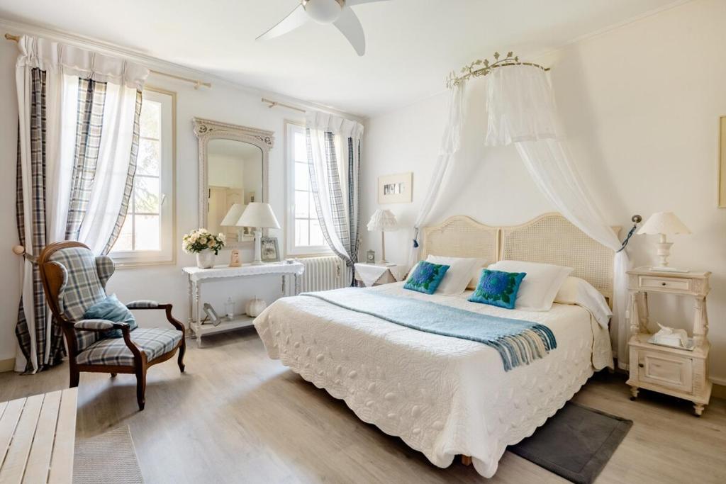 une chambre blanche avec un grand lit avec des oreillers bleus dans l'établissement Chambres d'hôtes de charme au REFUGE DU PEINTRE prés de St Emilion, à Sainte-Terre