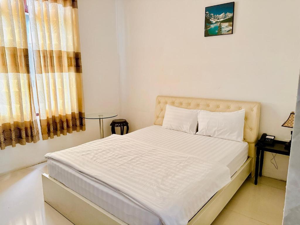 a white bedroom with a bed with white sheets and pillows at Khách sạn Nam Môn in Can Tho