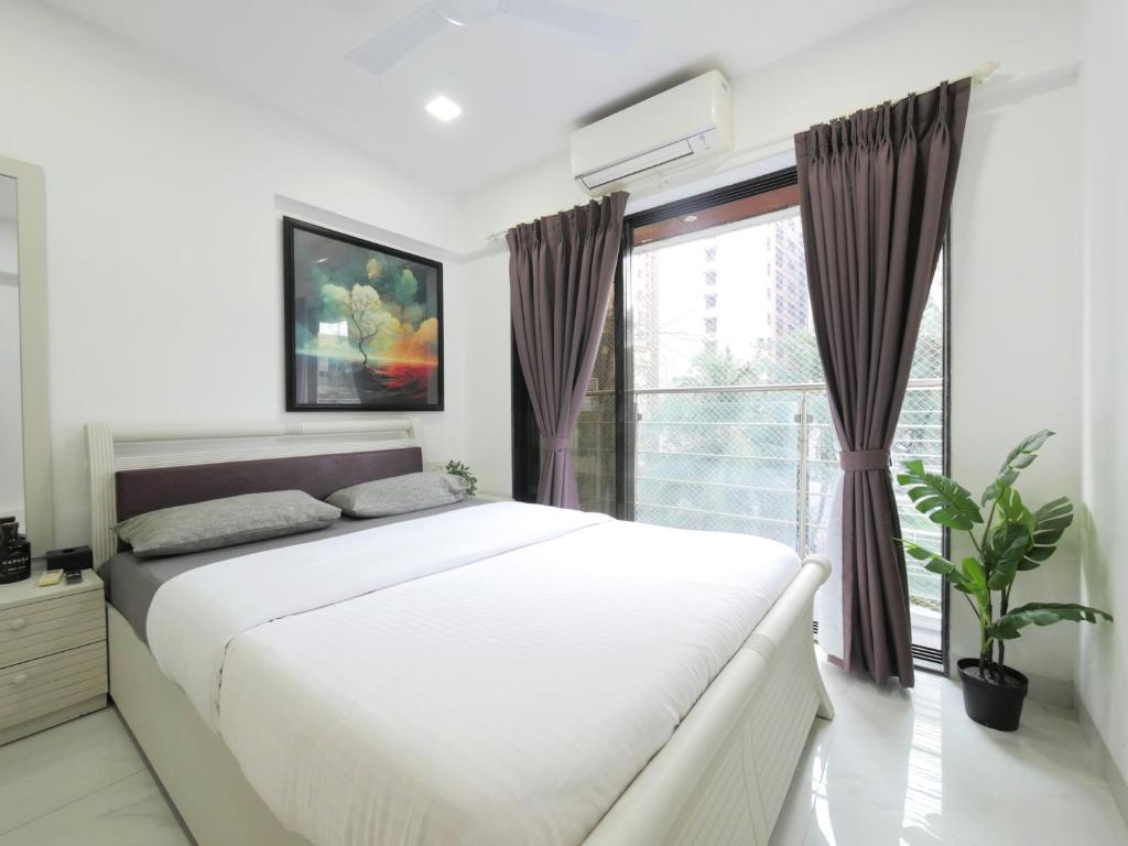 a bedroom with a large bed and a window at Athena 2BHK Khar W by The Bombay Home Company in Mumbai