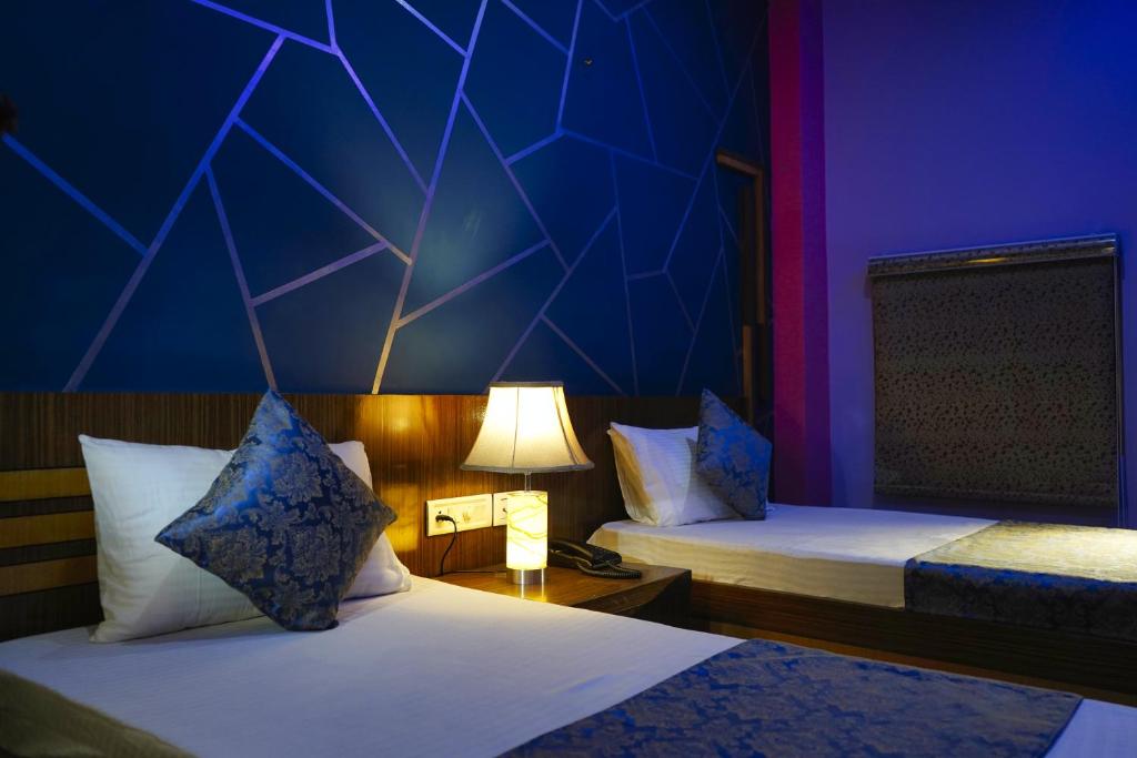 a room with two beds with a blue and purple wall at Hote Meghnath Palace in Dhupguri