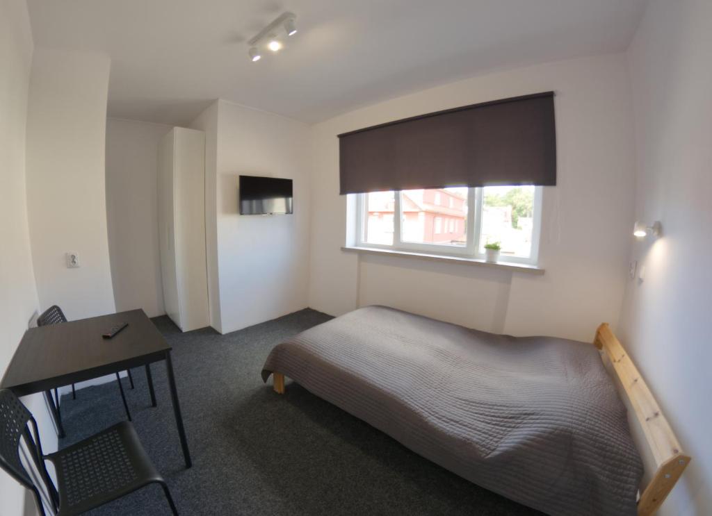 a bedroom with a bed and a desk and a window at Marynarska 57 in Darlowko
