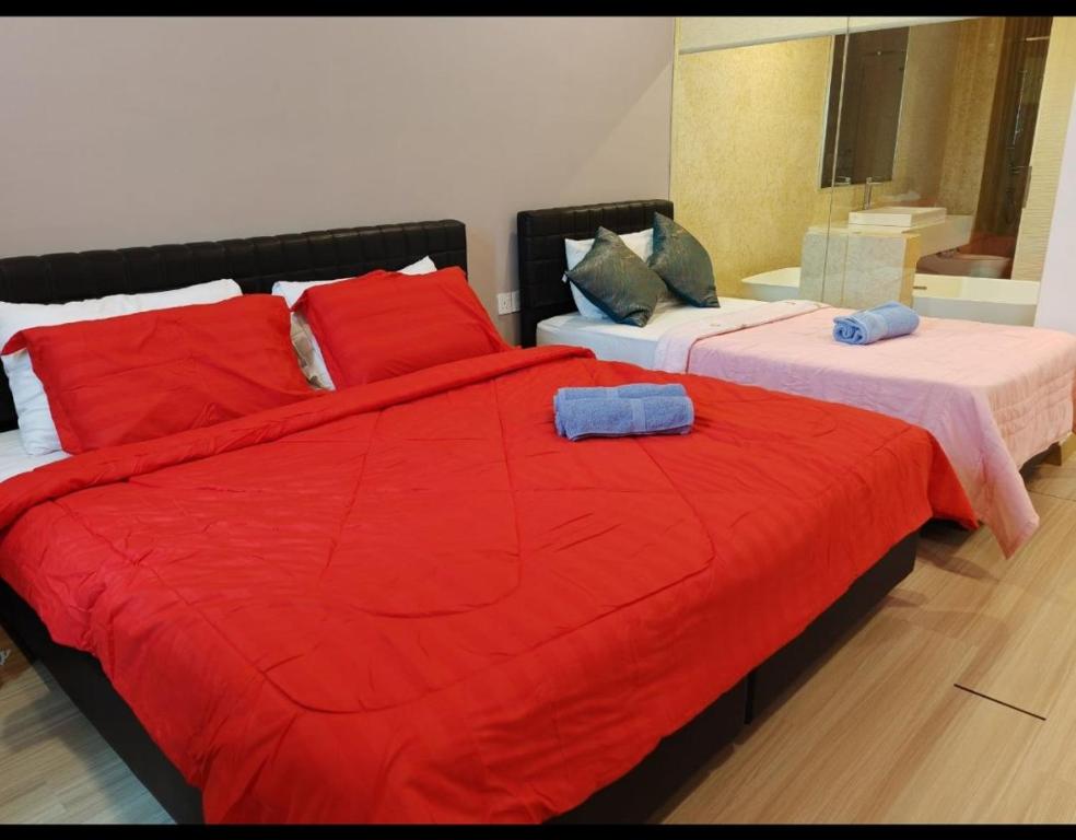 1 dormitorio con 2 camas, mantas rojas y almohadas en jazz suite 2 bedroom sea view apartment, en Tanjung Bungah