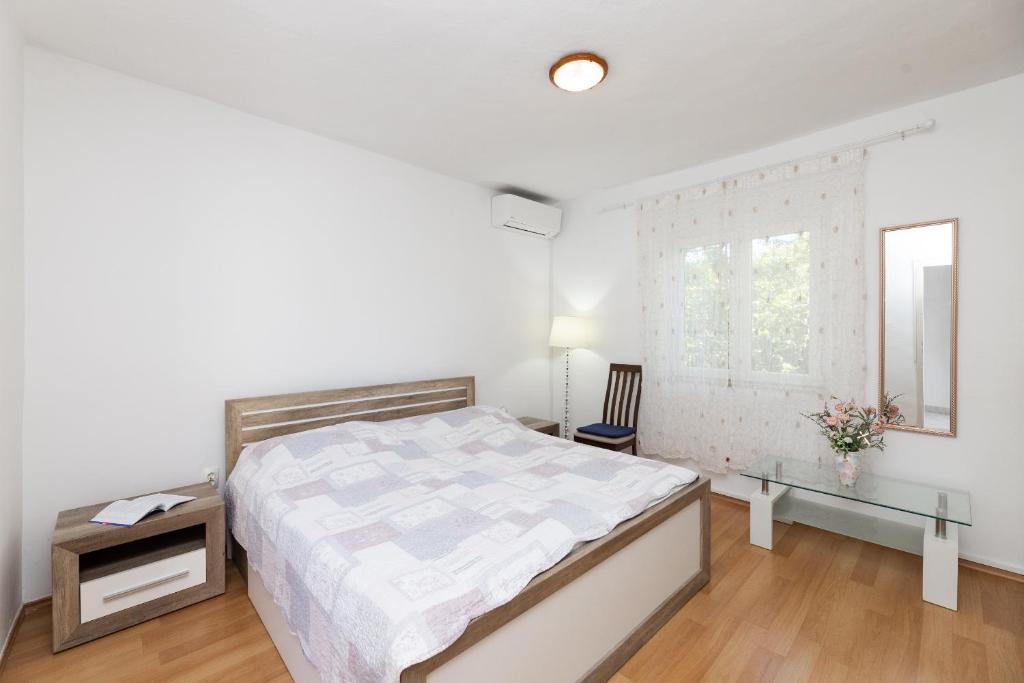 a white bedroom with a bed and a window at Apartman Angelina in Supetar