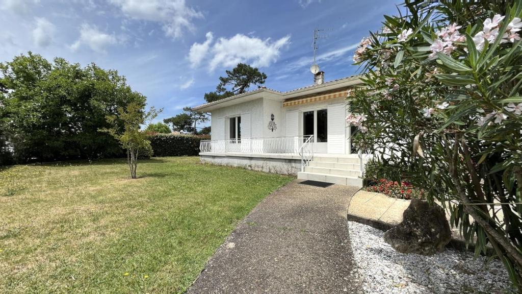 une maison blanche avec un jardin et une cour dans l'établissement Villa tout confort proche du port, à Gujan-Mestras