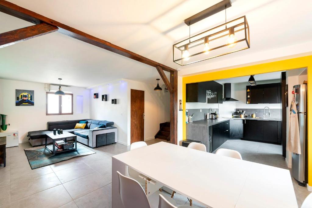 une cuisine et un salon avec une table et un canapé dans l'établissement Urban Comics - Appt climatisé 10p proche de Paris, à Brétigny-sur-Orge