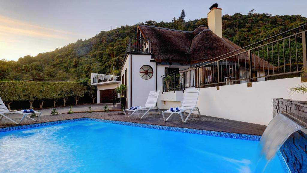 a villa with a swimming pool and a house at Cloverleigh Guest House in Wilderness