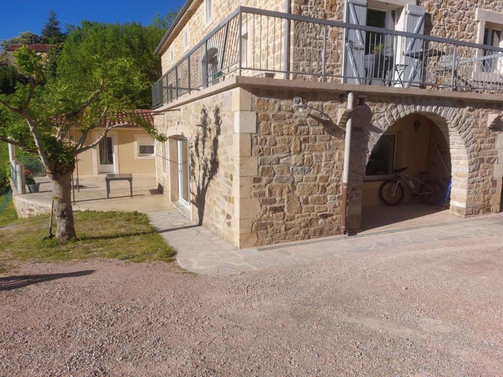 - un bâtiment en pierre avec un balcon et un arbre dans l'établissement La Bergerie, à Saint-Rome-de-Cernon