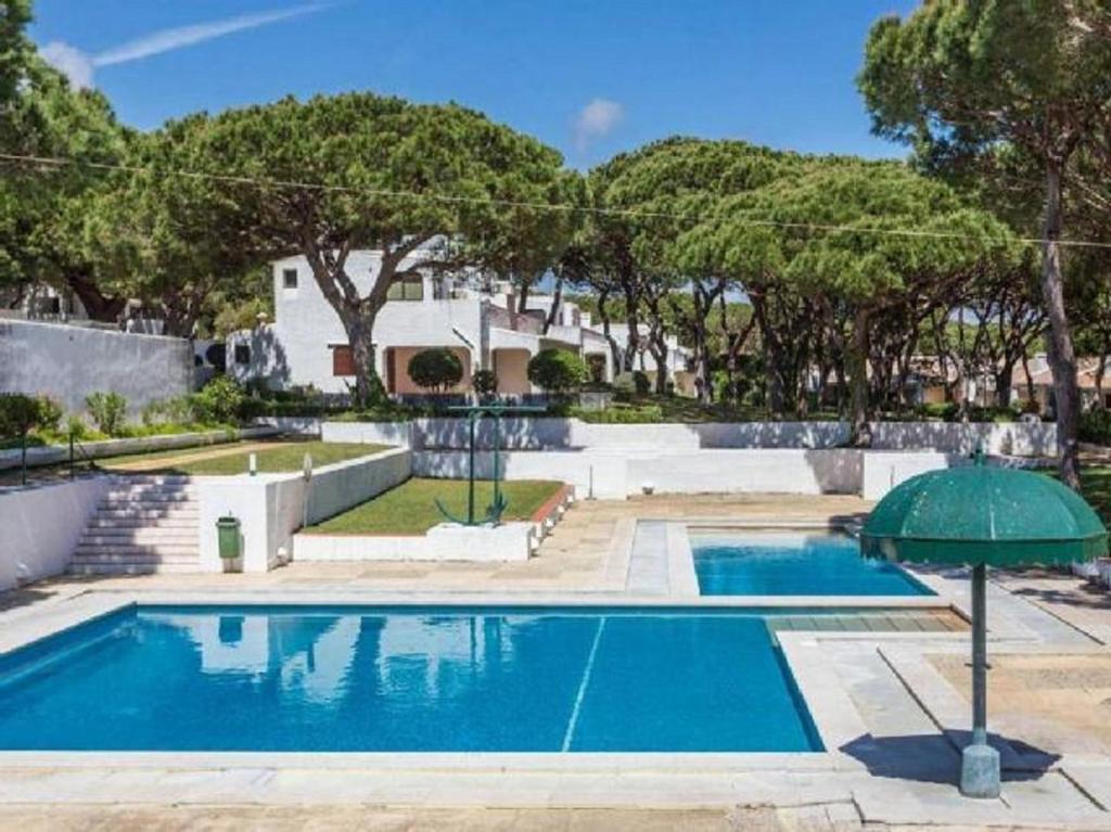 a swimming pool with an umbrella in front of a house at TAC - Açoteias Budget Studio in Olhos de Água