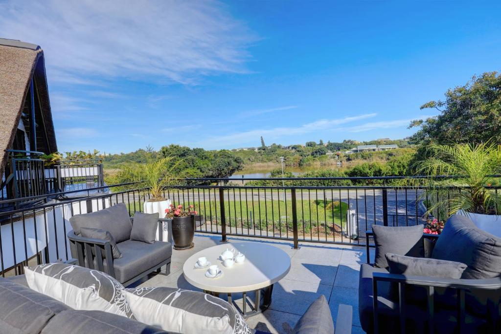 a balcony with a couch and chairs and a table at Cloverleigh Guest House in Wilderness