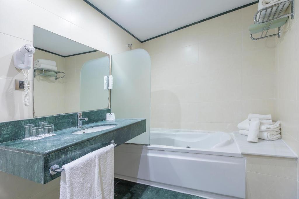 a bathroom with a sink and a tub and a mirror at Moon Dreams Calabahía in Cala del Moral
