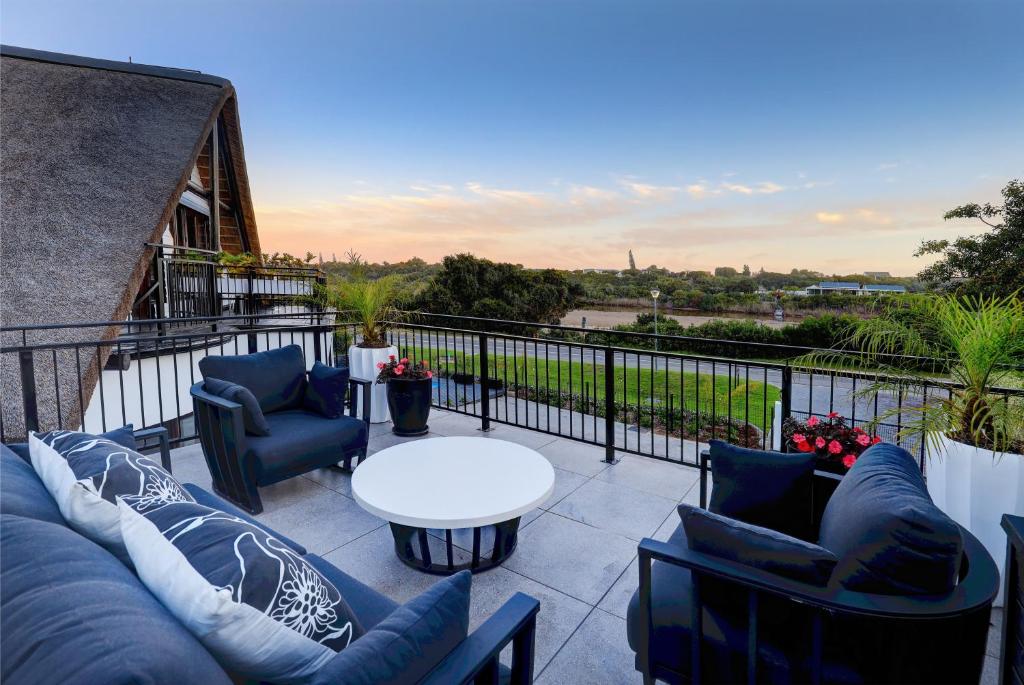 a patio with couches and a table on a balcony at Cloverleigh Guest House in Wilderness