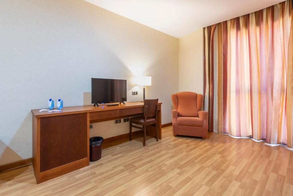 a hotel room with a desk with a television and a chair at Moon Dreams Calabahía in Cala del Moral
