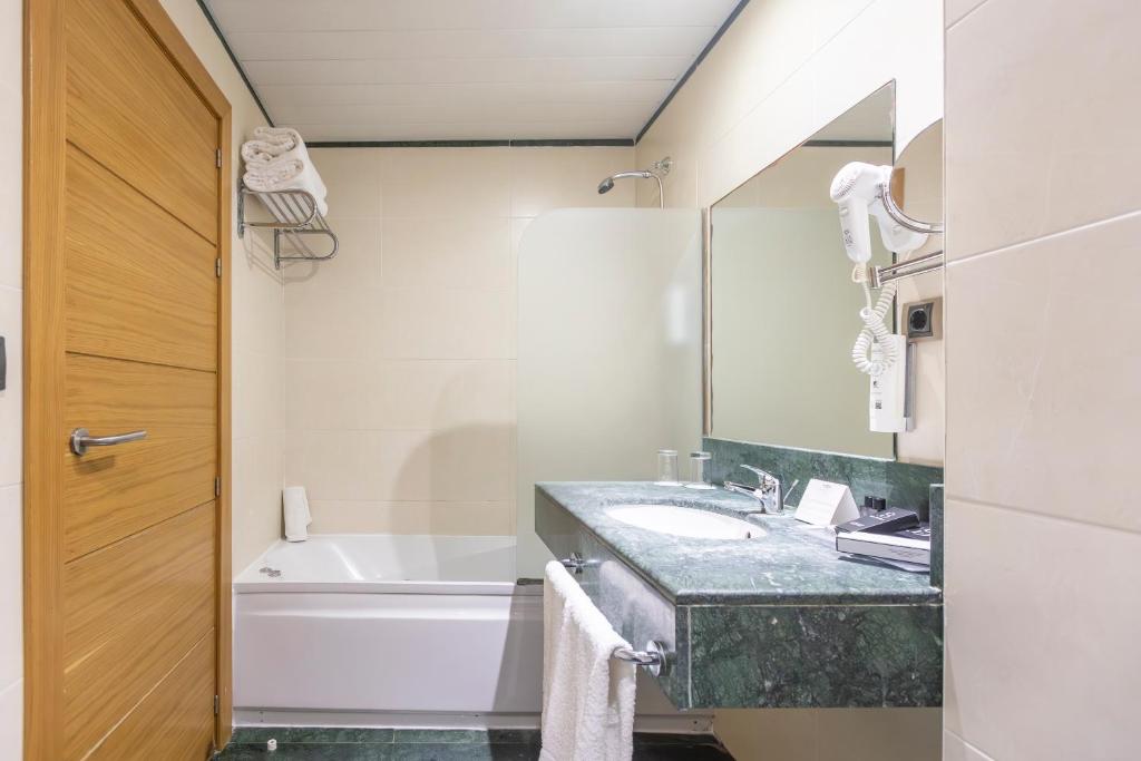 a bathroom with a sink and a tub and a mirror at Moon Dreams Calabahía in Cala del Moral