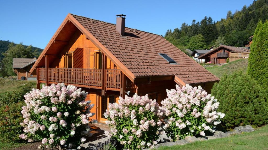 Cette maison en bois dispose d'un balcon et de fleurs. dans l'établissement Le Murmure du Ruisseau, à Xonrupt-Longemer