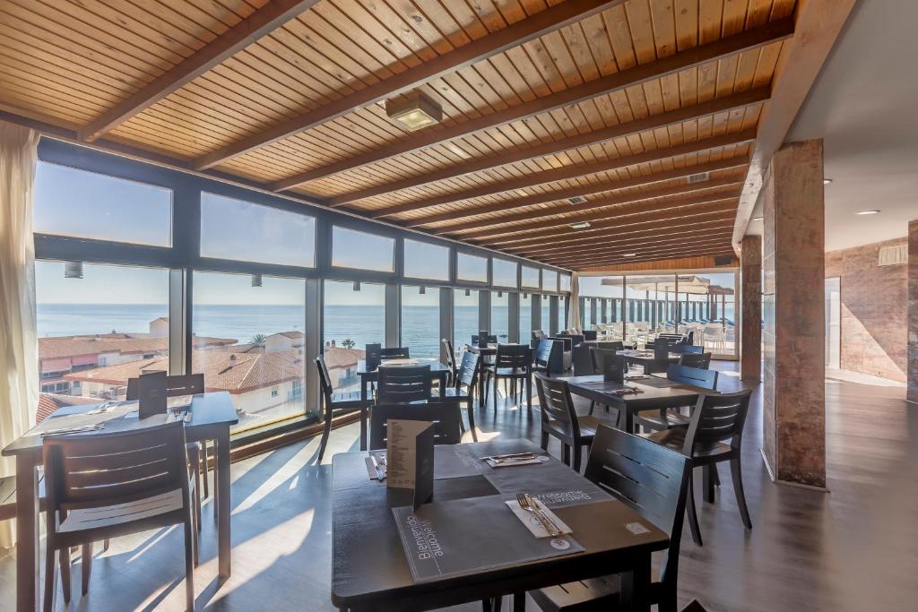 a restaurant with tables and chairs and a view of the ocean at Moon Dreams Calabahía in Cala del Moral
